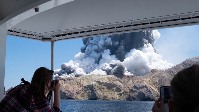 Turiști privesc și fac poze cu erupția vulcanului Whakaari în 2019