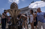 Rome, Italy. 14th July, 2023. A tourist cools his head at a public fountain in Piazza Venezia. Southern Europe faces a heatwave, bringing potentially record-breaking temperatures. Credit: Oliver Weiken/dpa/Alamy Live News