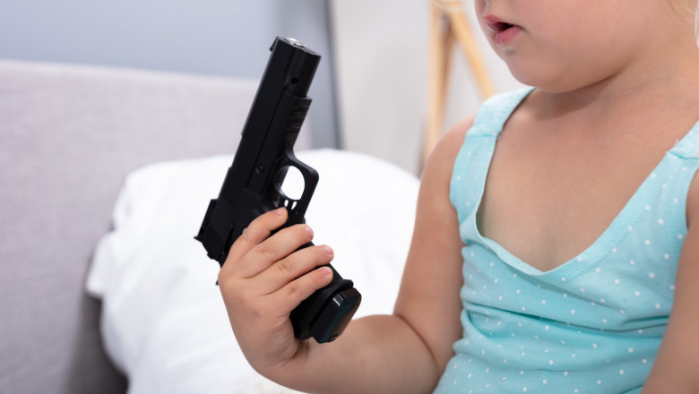 un copil tine in mana o arma