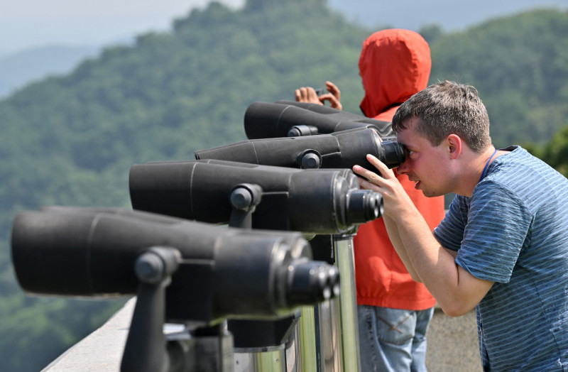 Turiști la DMZ în Coreea privesc prin binoclu