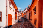 Narrow cobbled alley with multicoloured vibrant houses in Sighisoara village, Romania