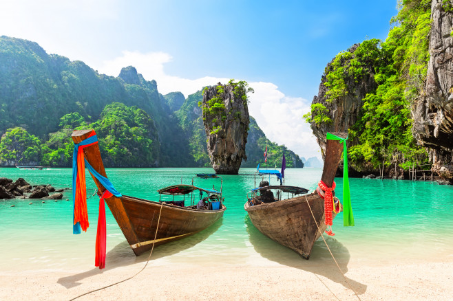 Travel photo of James Bond island with thai traditional wooden longtail boat and beautiful sand beach in Phang Nga bay, Thailand.