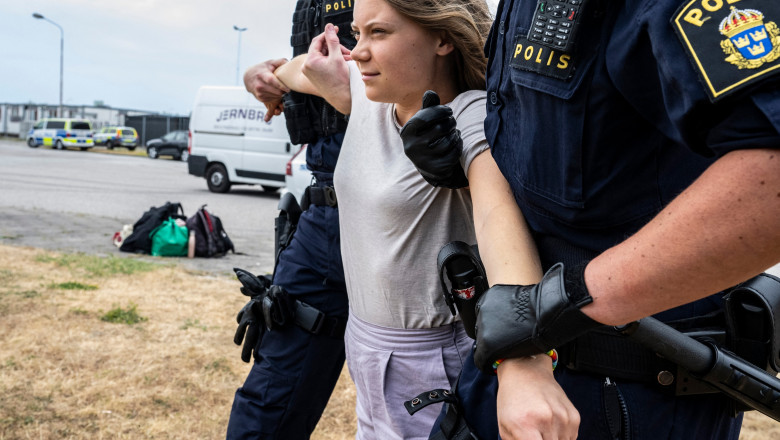 Greta Thunberg ținuta de mâini de doi polițiști