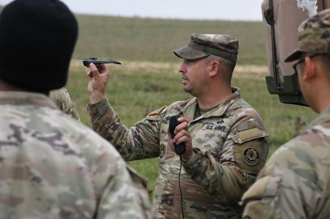 U.S. Army Sgt. 1st Class Jeremy Garduno, assigned to Palehorse Troop, 4th Squadron, 2nd Cavalry Regiment, demonstrates the capabilities of the PD-100 Black Hornet Nano Drone to fellow Soldiers during a situational training exercise at the 7th Army Trainin