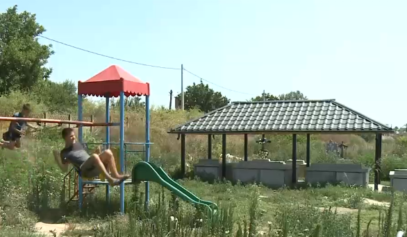 Loc de joacă în cimitir. Copiii din Dăbuleni se dau în leagăn printre morminte