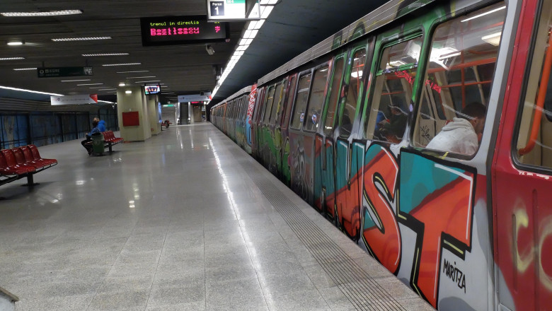 un metrou, stationând în stație, se vede peronul și se vede un om