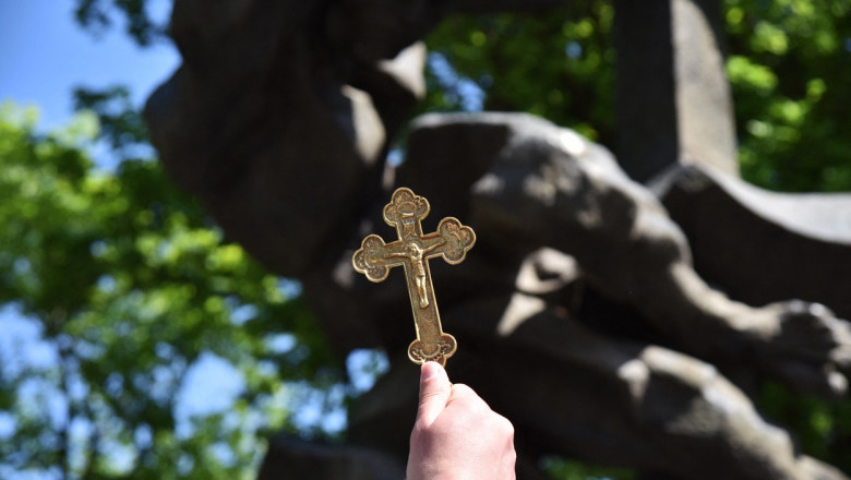 un preot ortodox tine o cruce in mana ridicata