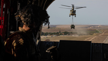 militar american se uită din elicopter la un alt elicopter de transport al SUA în apropiere de baza Mihail Kogălniceanu, România