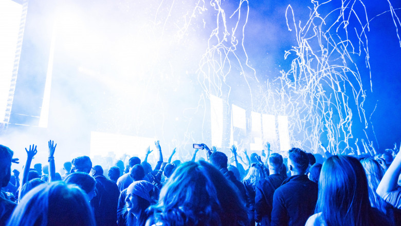 un grup de oameni danseaza si aruncă cu confetti la un concert din cadrul festivalului electric castle