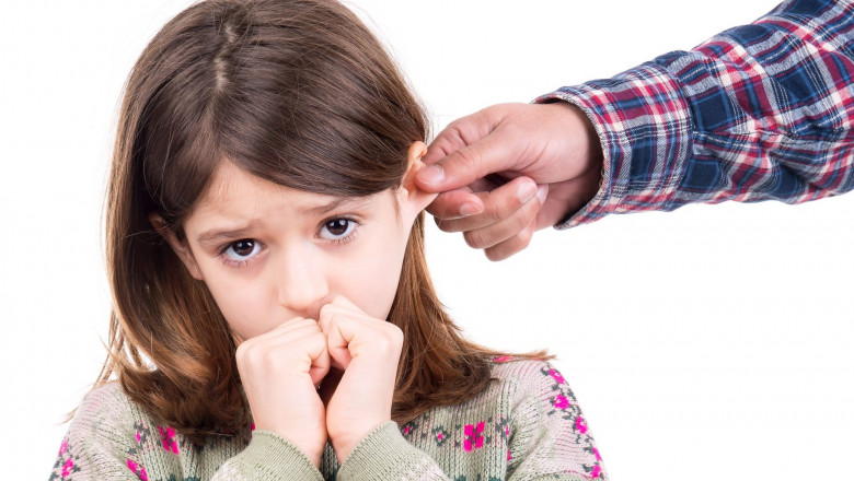 Young girl being punished with ear pulling
