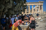 Athen, Greece. 14th July, 2023. Tourists cool off at a water fountain during their visit to the Parthenon Temple on the Acropolis Hill on this hot day. The Ministry of Culture has decided to close the archaeological site during the hottest hours of the da