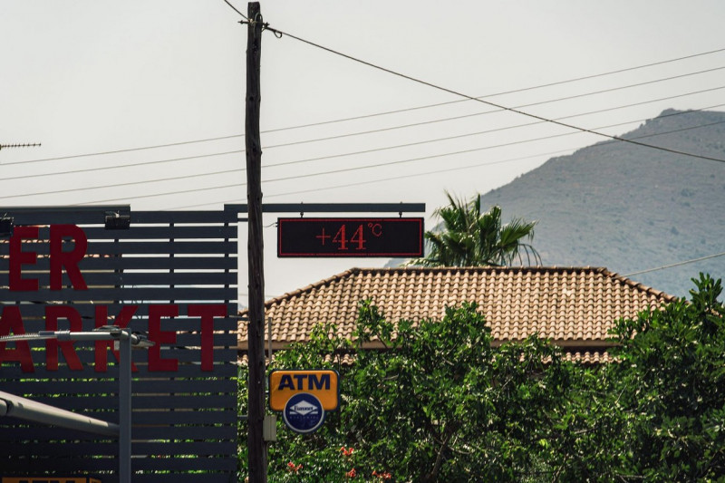 Heatwave 44 degrees Celsius outdoors digital display. Hot temperature large illuminated street thermometer sign hanging outside on a summer day in Zakynthos, Greece.