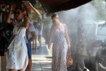 Thessaloniki, Greece, 27th July 2015. Tourists walk through waters droplets sprayed by sprinklers in Thessaloniki, northern Greece. Greeks have been advised to protect themselves from the heat as temperatures are expected to rise this week, mainly in m