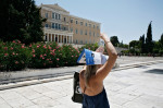 Heatwave in Athens. Woman with a brochure in her head trying to protect herself from the sun. Syntagma Square, Athens, Greece.