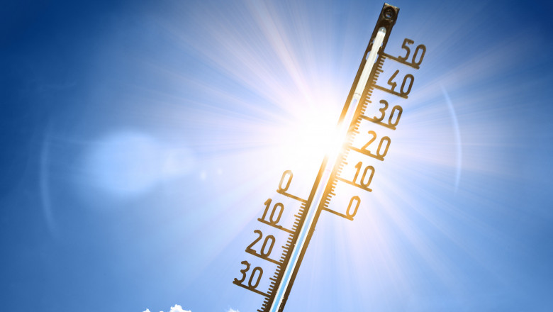 un termometru cu gradatii în Celsius arată temperaturi mari, pe fundal este cerul si soarele