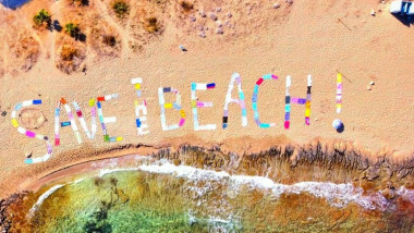 save the beach scris cu prosoape pe o plaja in grecia