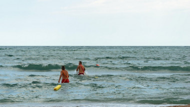 Neptun, Romania - July 8, 2017: Two lifeguards enter in the Black Sea to save someone from drowning on the romanian seaside beach! Neptun, Constanta,