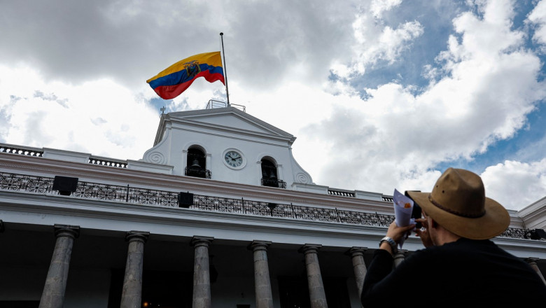Un bărbat fotografiază un steag al Ecuadorului pe palatul prezidențial
