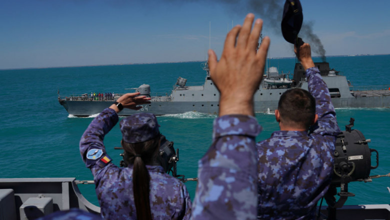 marinari români salută o navă care trece pe lângă ei