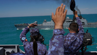 marinari români salută o navă care trece pe lângă ei