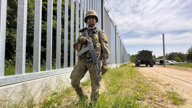 Soldat cu o pușcă automată lângă zidul de la granița Poloniei cu Belarusul