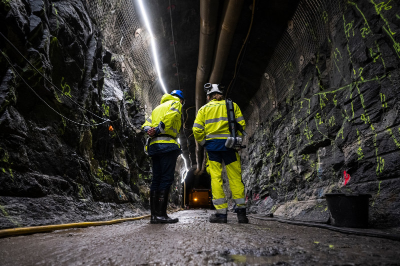 bărbați în costume de protecție într-un tunel întunecat