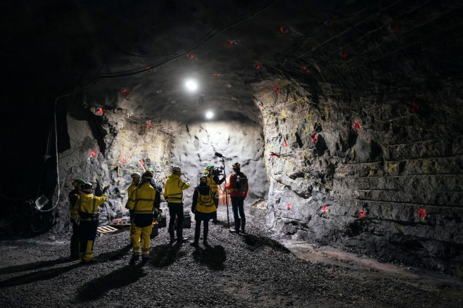 bărbați în costume de protecție într-un tunel întunecat