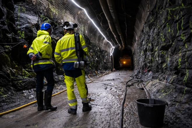 bărbați în costume de protecție într-un tunel întunecat