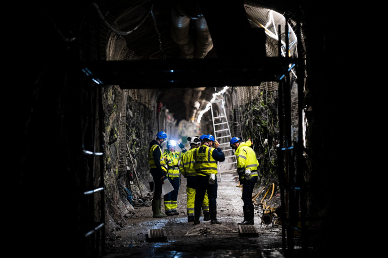 bărbați în costume de protecție într-un tunel întunecat