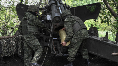Artileriști ruși încarcă un obuz pe țeava unui tun, unul dintre ei poartă adidași