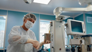 medic cu masca si halat langa un aparat in spital