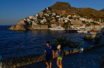 Hydra, Greece. 24th July, 2020. A couple walks hand in hand past the harbour. The island of Hydra, which covers almost 50 square kilometres, is 65 kilometres south-west of Athens. Cars, neon signs and plastic chairs are prohibited on the island. Credit: A