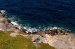 Hydra, Greece. 24th July, 2020. People bask in the sun by the water. The island of Hydra, which covers almost 50 square kilometres, is 65 kilometres south-west of Athens. Cars, neon signs and plastic chairs are prohibited on the island. Credit: Angelos Tz