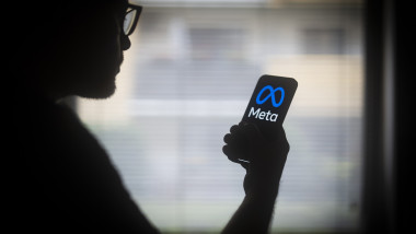 om cu telefon în mână cu logo-ul Meta pe ecran