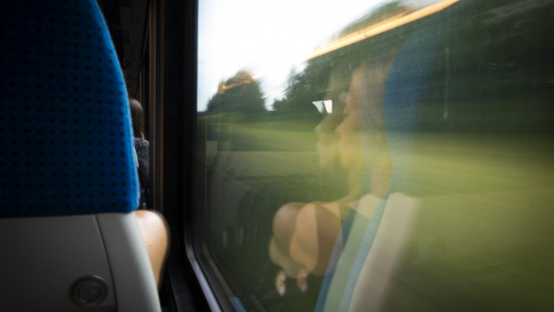 femeie care sta in tren si se uita pe geam