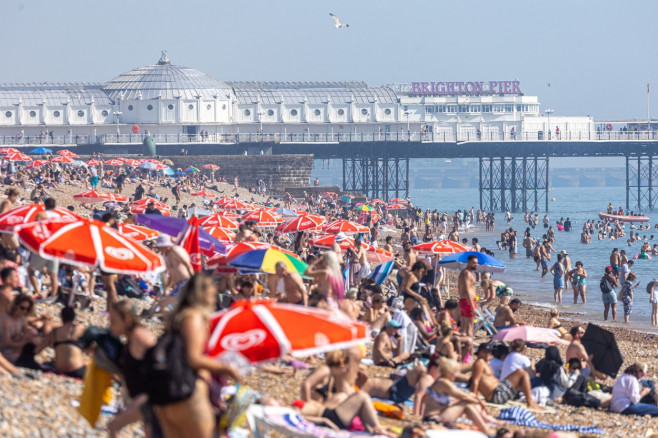 Sunbathers and swimmers on Brighton beach East Sussex, UK.