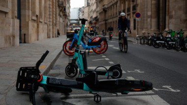 Electric scooters and electric bikes are seen parked on divided field on the street in Paris
