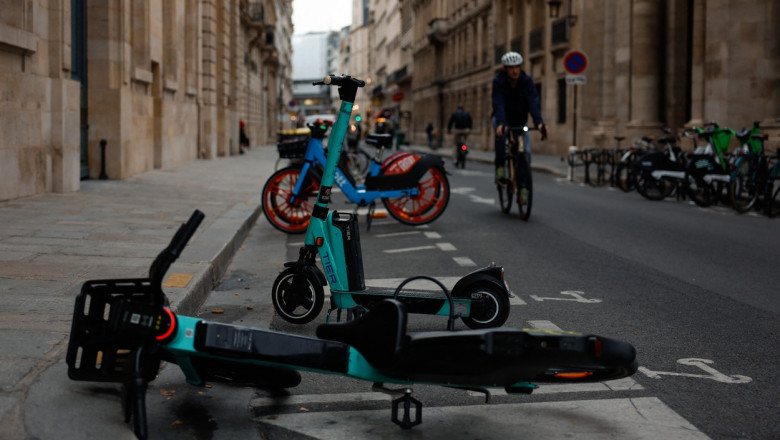 Electric scooters and electric bikes are seen parked on divided field on the street in Paris