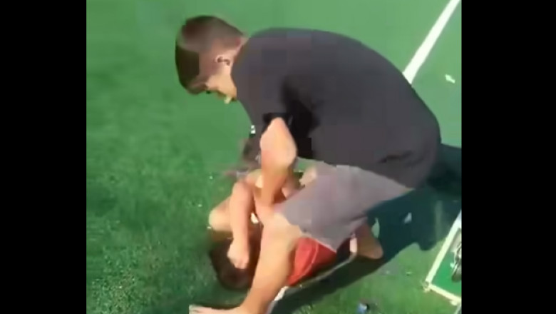 un copil il bate pe un altul pe un teren de sport