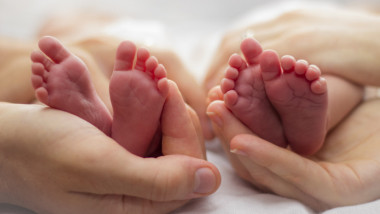 patru picioruse de bebeluși tinute în mâini
