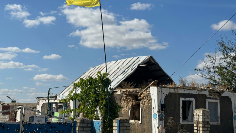 casa distrusa cu steagul ucrainei fluturand deasupra