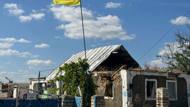 casa distrusa cu steagul ucrainei fluturand deasupra
