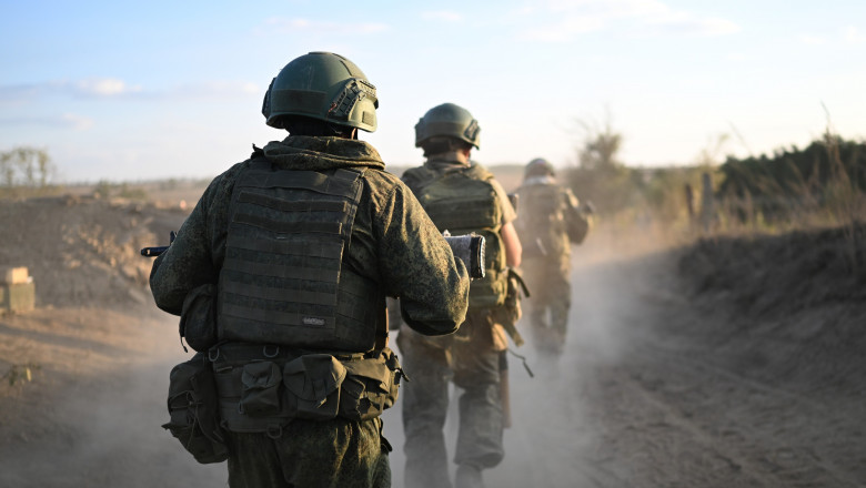 Militari ruși, văzuți din spate, mărșăluiesc pe un drum