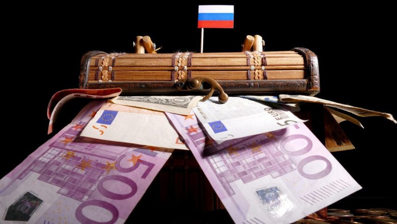 Cufăr cu bancnote de euro pe care este așezat steagul Rusiei