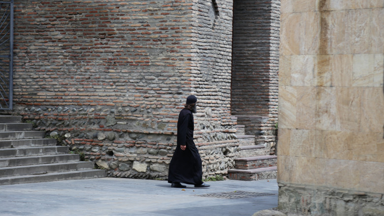 calugar ortodox merge pe langa zidulunei biserici