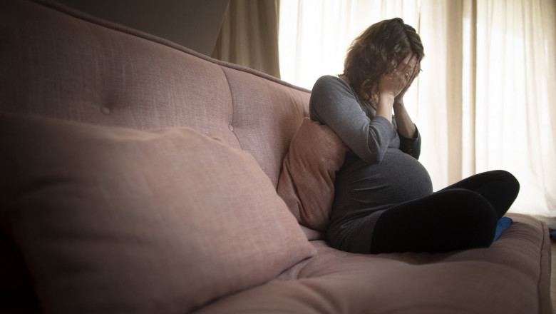 femeie însărcinată tristă pe o canapea