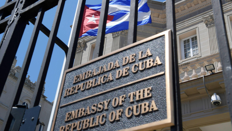 ambasada cubei, plăcută de identificare pe gard, cu clădirea în spate și steagul cubei fluturând