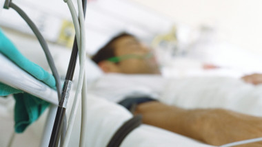 barbat intr-un pat de spital si aparatura medicala
