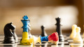 Chess kings in the colors of the flag of Ukraine and the flag of Russia on a wooden table in the sun on the street, chess and chess games, politics
