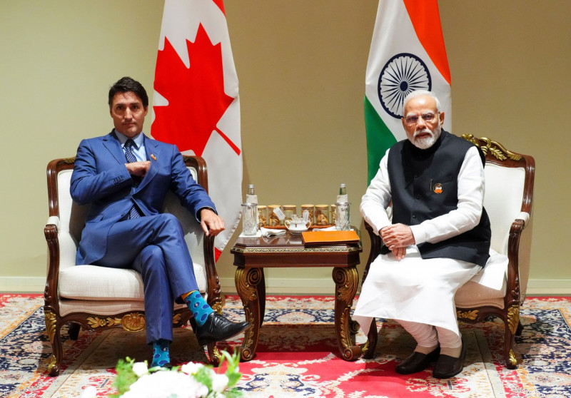 Justin Trudeau și Narendra Modi pe scaune la masă, cu steagurile Canadei și Indiei în spate